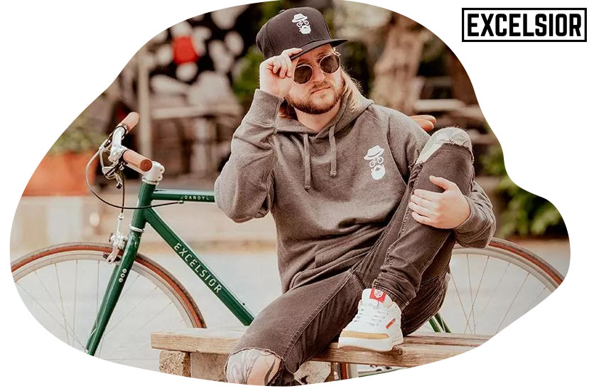 Lässiger Radfahrer sitzt vor seinem Urban-Bike der Marke Excelsior