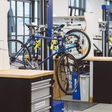 Aufgebockte Fahrräder mit blauer Lackierung von der Marke VSF Fahrradmanufaktur. Sie stehen in der Werkstatt von FahrRad R18 und werden wohl bald repariert.
