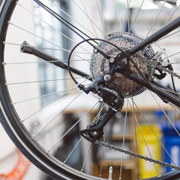 Eine Nahaufnahme von einem Hinterrad samt Kettenschaltung. Das dazugehörige Fahrrad steht in der Werkstatt von FahrRad R18 in München.