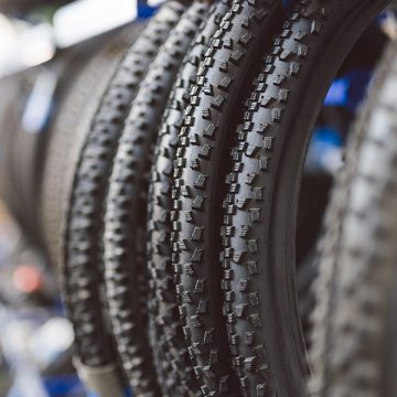 Reifen für Fahrräder mit verschiedenen Profilen stehen oder hängen im Ladengeschäft von R18, bereit für den Verkauf.